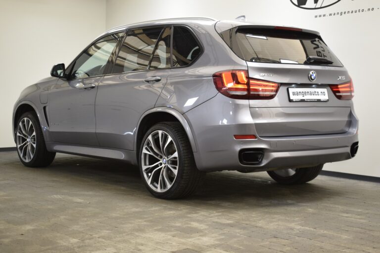 A gray BMW X5 SUV is parked indoors, showcasing its rear and side profile. The car is clean and features modern design elements and alloy wheels.