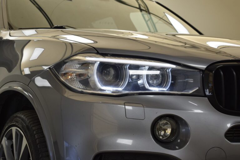 Close-up of a metallic grey SUV's front, showcasing the headlight, fog light, and part of the front wheel.