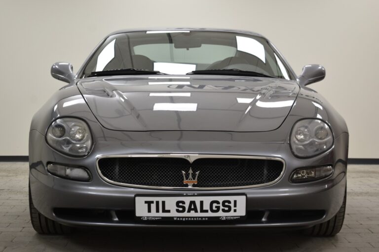 Front view of a silver Maserati sports car with a "TIL SALGS!" sign on the license plate, indicating it is for sale.