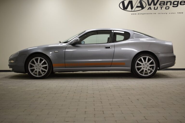 A silver two-door luxury sports coupe is parked indoors on a tiled floor. The car features large alloy wheels and a sleek design, with "Wangen Auto" signage visible in the background.