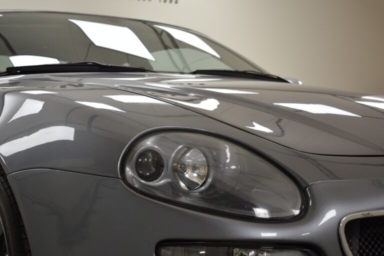 Close-up view of the front end of a gray sports car showcasing its headlight and aerodynamic design.