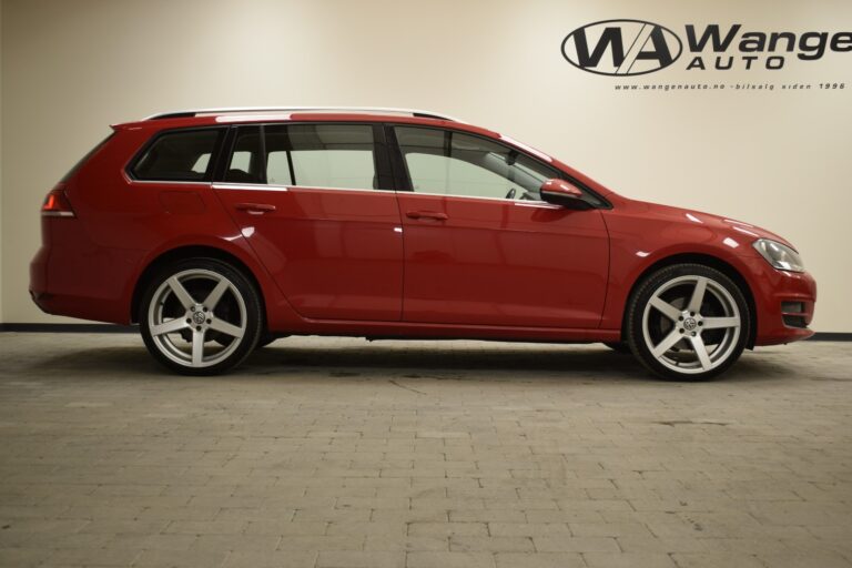 A side view of a red station wagon parked indoors. The vehicle has silver alloy wheels and is positioned against a plain wall with the "Wanger Auto" logo in the background.