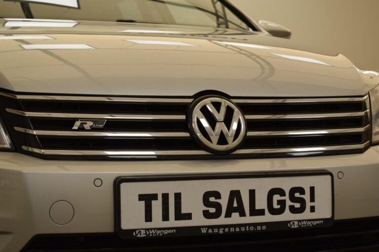 Close-up of the front of a Volkswagen car with an "R-Line" badge and a license plate that reads "TIL SALGS!" indicating the car is for sale.