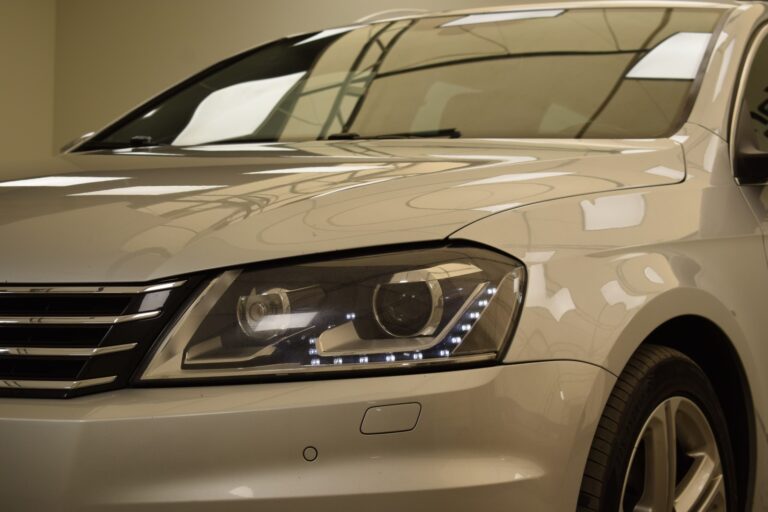 Close-up view of the front left side of a silver car, showing the headlight and part of the grille.