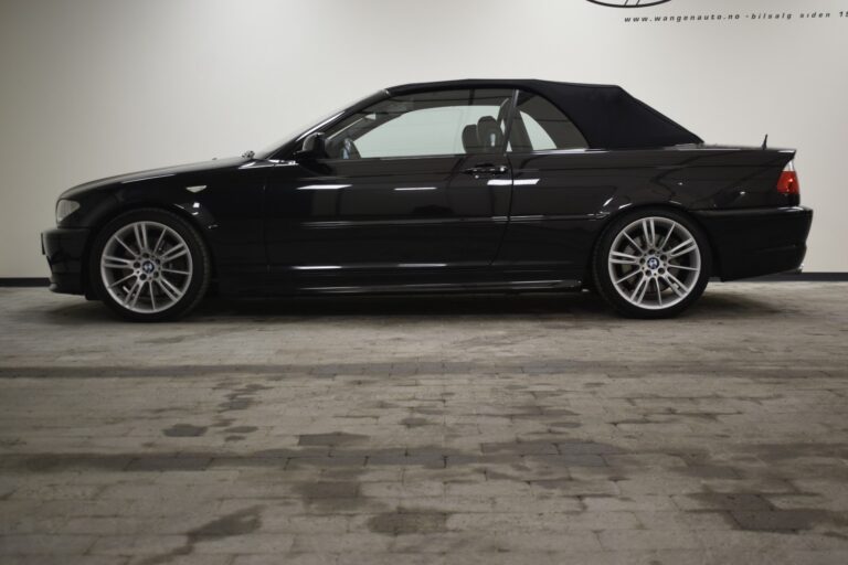 Side view of a black BMW convertible with the top closed, parked indoors on a gray tiled floor.