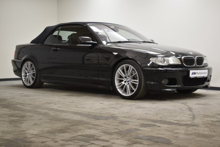 A black convertible BMW parked indoors on a concrete floor with a light background.