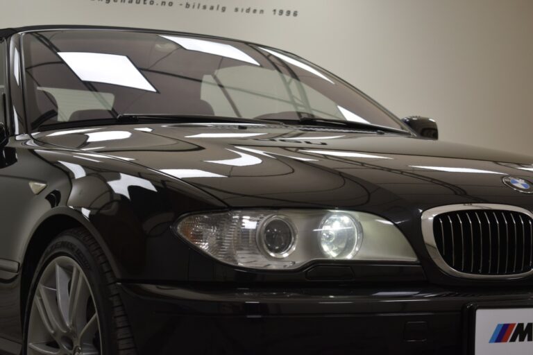 A close-up view of the front of a black BMW sedan, focusing on the headlights and front grille.