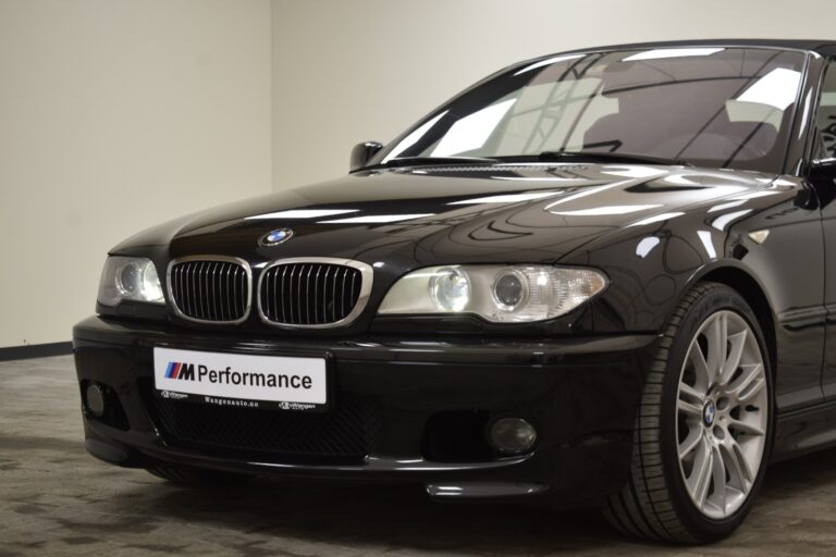 A black BMW car with an M Performance badge is parked indoors. The front of the vehicle and part of the driver's side are visible.