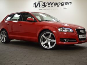 A red Audi hatchback car parked indoors with the "Wangen Auto" dealership sign visible in the background.