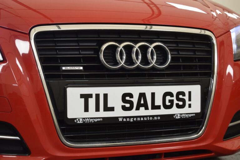 Close-up of the front grille of a red Audi car with a "TIL SALGS" sign, indicating it is for sale.