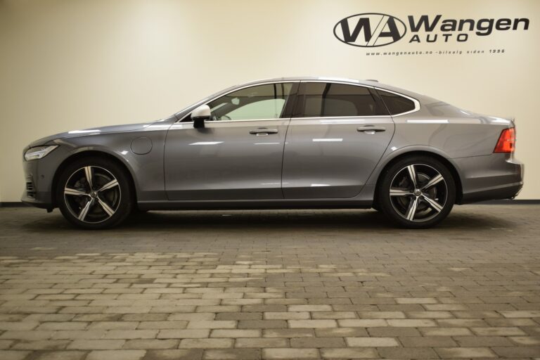 A side view of a gray sedan inside a showroom with a "Wangen Auto" logo on the wall in the background.