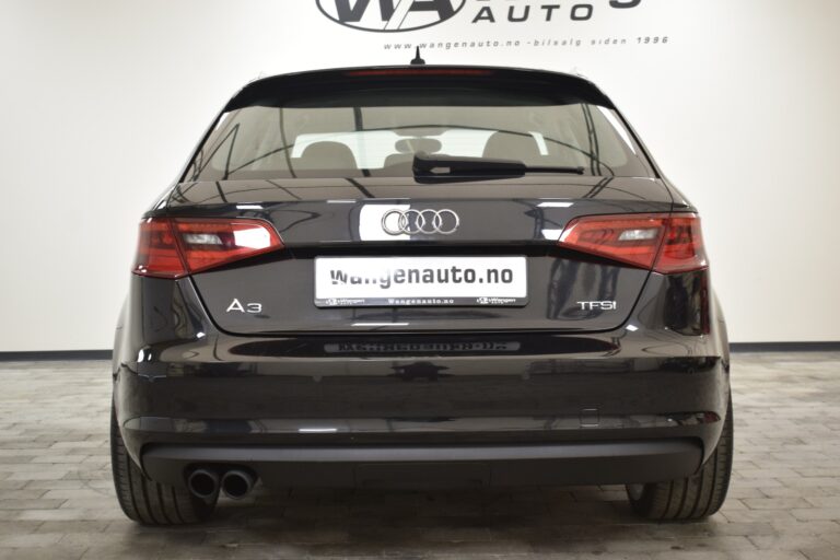 Rear view of a black Audi A3 TFSI parked indoors with a dealership banner in the background.