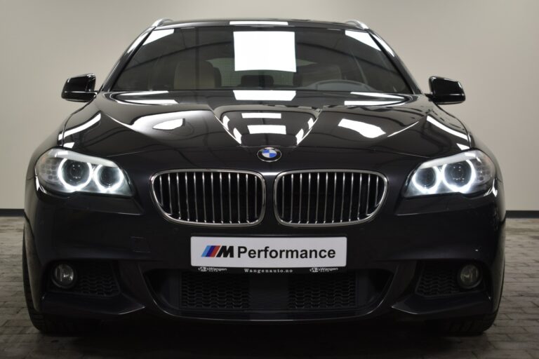 Front view of a black BMW car with illuminated headlights. The license plate reads "M Performance.