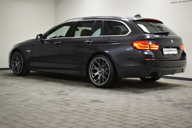 A dark gray BMW station wagon parked indoors on a tiled floor.