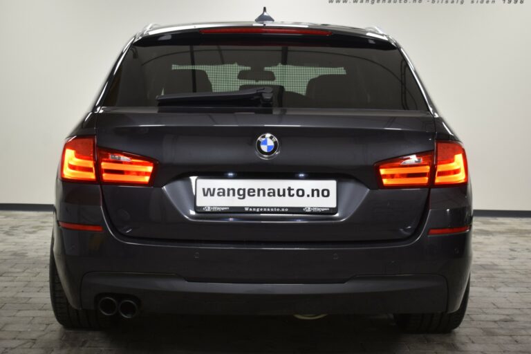 Rear view of a black BMW station wagon with illuminated tail lights, parked indoors with a "wangenauto.no" license plate.