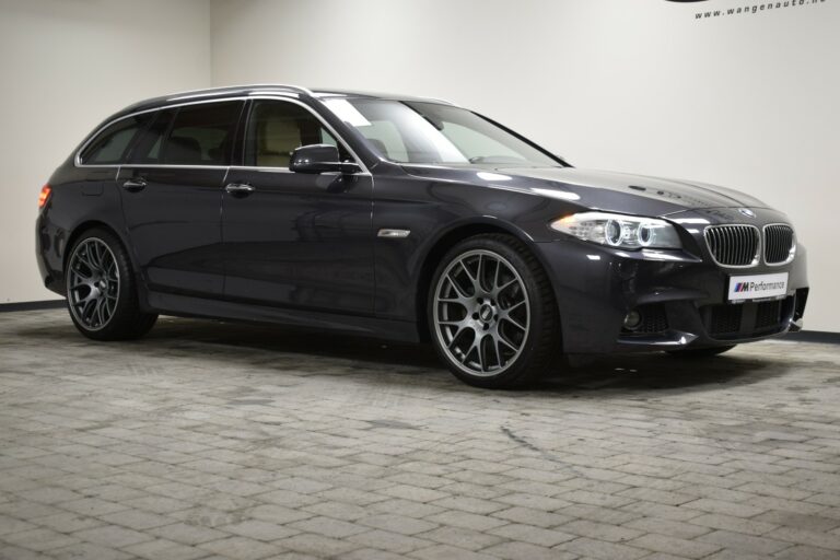 A dark gray station wagon parked indoors on a tiled floor, viewed from the side.