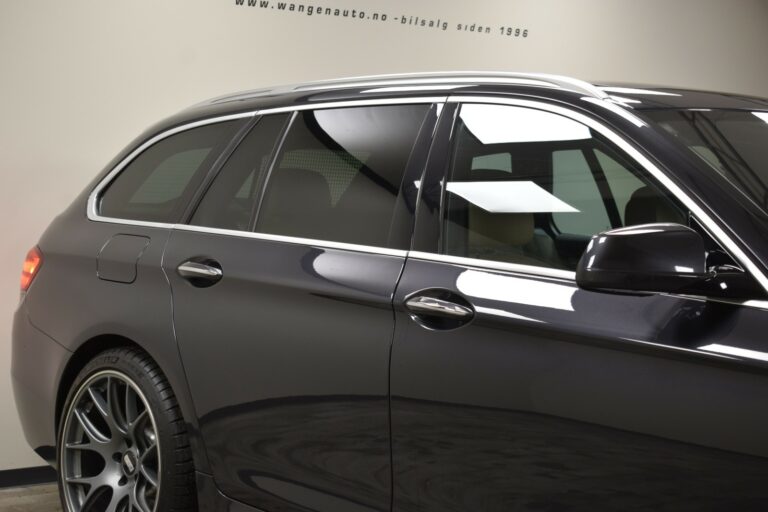 Side view of a dark-colored station wagon car with tinted windows and alloy wheels, parked indoors.