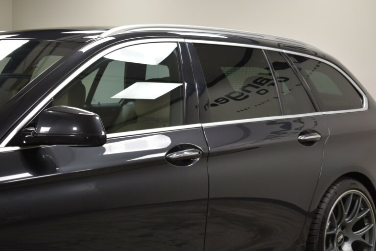 Side view of a black station wagon with tinted windows and alloy wheels, parked indoors.