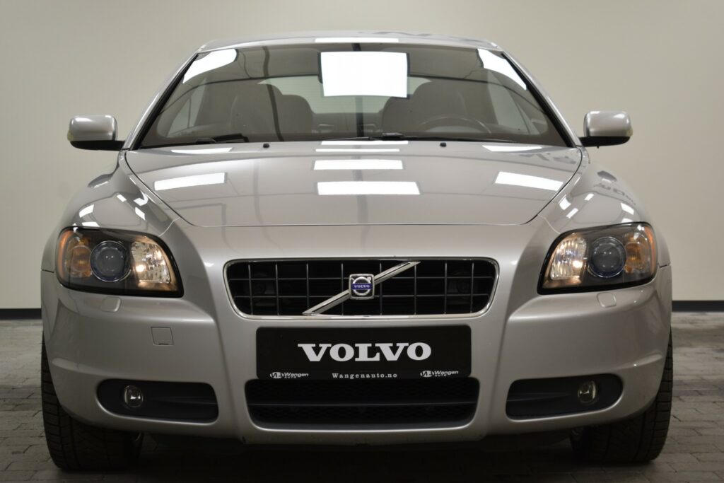 A silver Volvo car is shown from the front, displaying its grille, headlights, and logo.