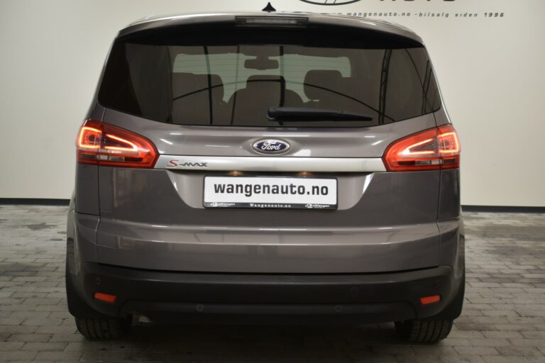 Rear view of a grey Ford S-Max parked indoors, showcasing its taillights and license plate with "wangenauto.no" printed on it.