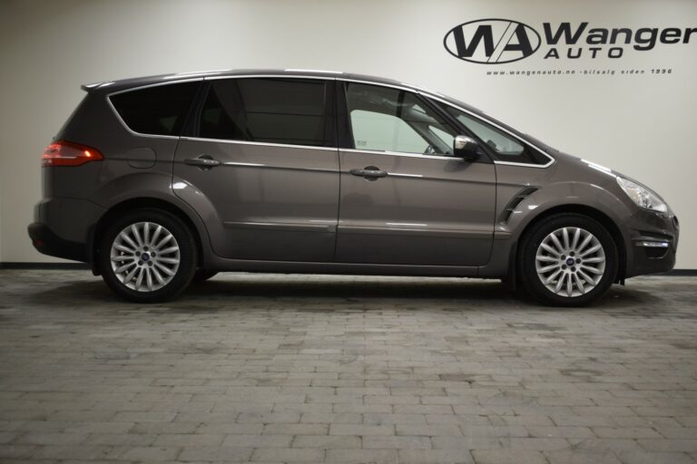 Side view of a gray minivan parked indoors on a tiled floor with "Wanger Auto" signage in the background.