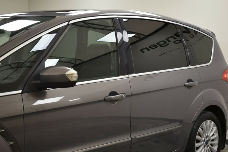 Side view of a gray car with tinted windows and a visible side mirror, parked in a garage.