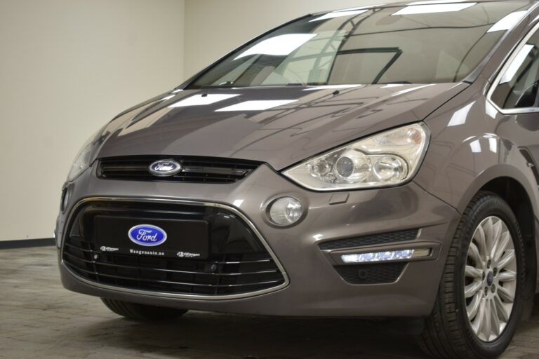 A gray Ford car is parked indoors, showing the front view with headlights, grille, and Ford logo visible.