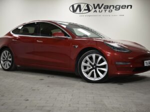 Red electric car parked indoors at Wangen Auto dealership.