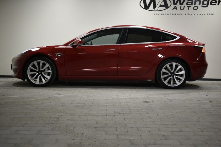 Side view of a red sedan parked indoors with the logo "Wanger Auto" on the wall behind.