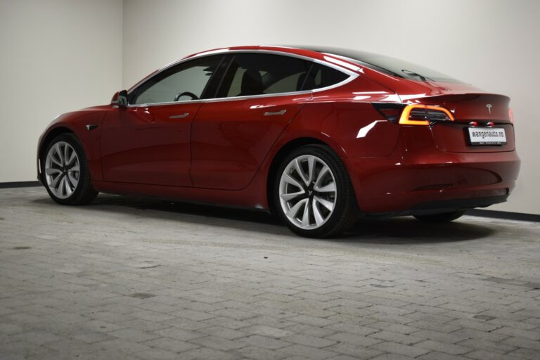 A red sedan in a dimly lit room, viewed from the rear side.