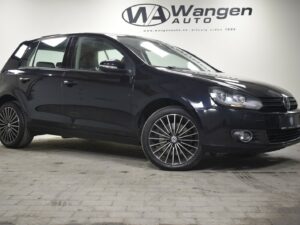 Black Volkswagen hatchback car displayed indoors with Wangen Auto logo on the wall in the background.