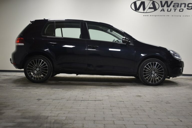 Side view of a black hatchback car with alloy wheels, parked indoors on a tiled floor.