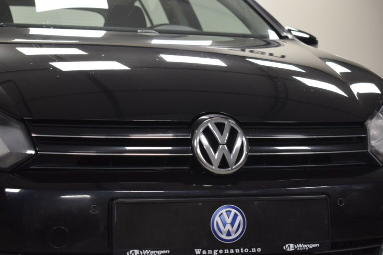 Close-up of a black Volkswagen car front, showing the logo on the grille and a website URL on the license plate placeholder.