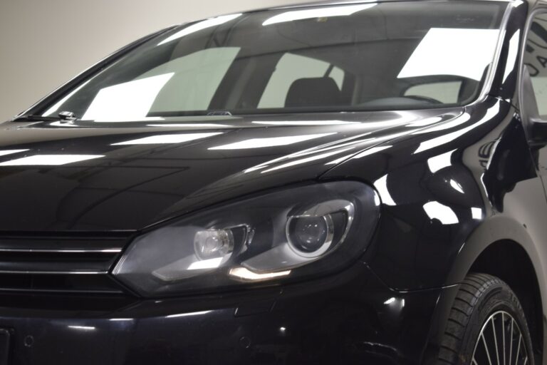 Close-up of the front right side of a black car, showing the headlight, grille, and part of the windshield.