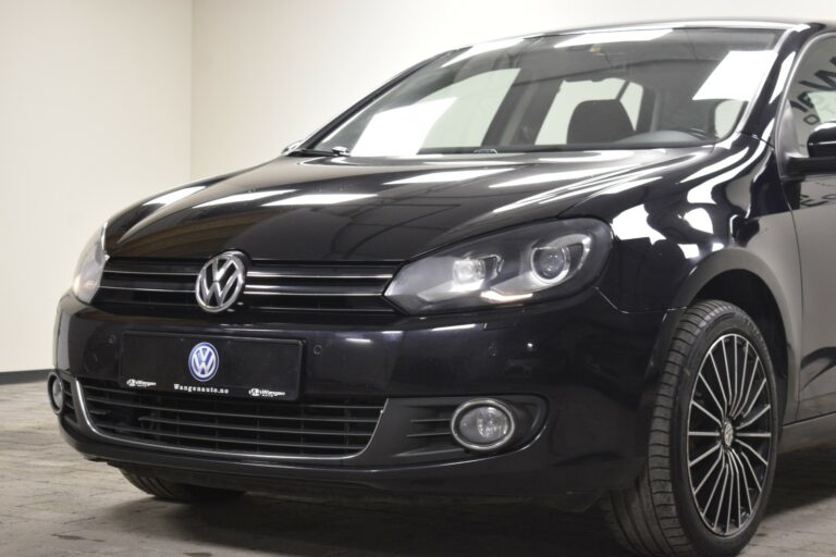 A black Volkswagen Golf with stylish alloy wheels is parked indoors on a tiled floor.