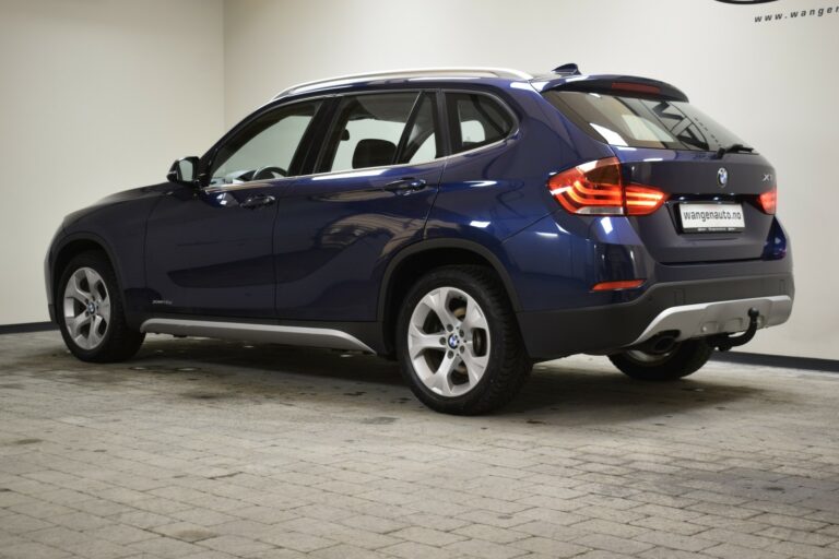 Blue SUV parked indoors on a tiled floor, viewed from the rear three-quarters.