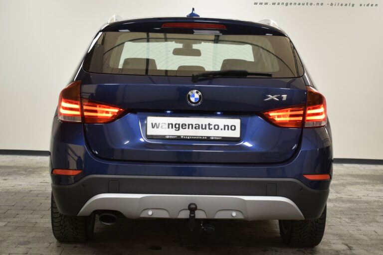 Rear view of a blue BMW X1 parked indoors. License plate shows "wangenauto.no.