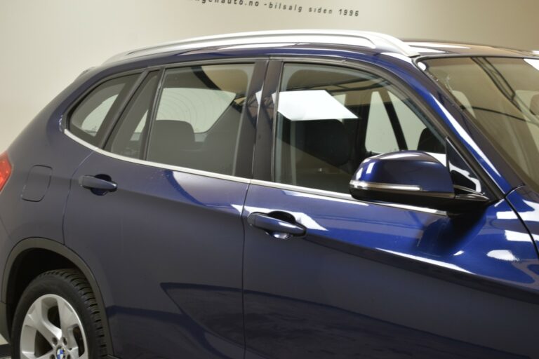 Close-up of a blue SUV focusing on the side windows, mirror, and door, with a reflection on the glossy finish.