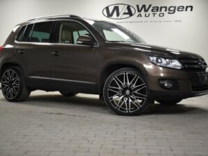 A brown Volkswagen SUV is parked on a tiled floor in front of a wall with the "Wangen Auto" logo.