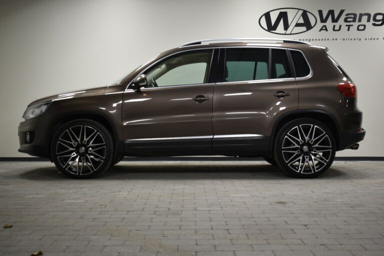 Side view of a brown SUV with large rims parked indoors against a beige wall with "Wang Auto" logo.