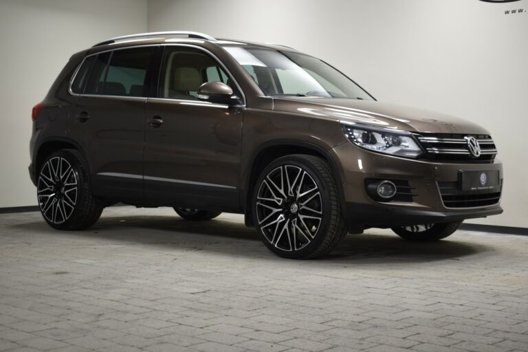 A brown Volkswagen SUV is parked indoors on a tiled surface, showcasing its shiny finish and large black wheels.