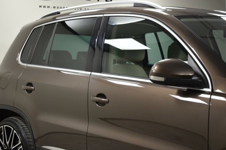 Side view of a brown SUV, focusing on the windows, door, and side mirror.