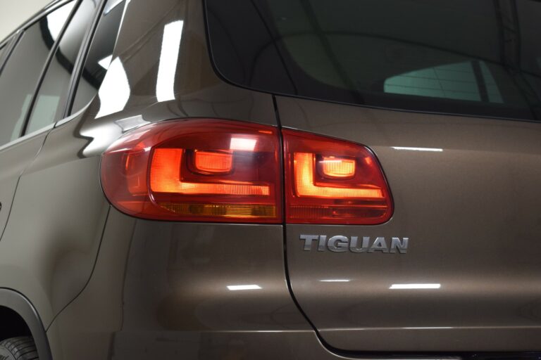 Close-up of a brown SUV with the word "Tiguan" and illuminated rear lights.