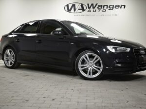 Black Audi A3 on a showroom floor with a Wangen Auto sign in the background.