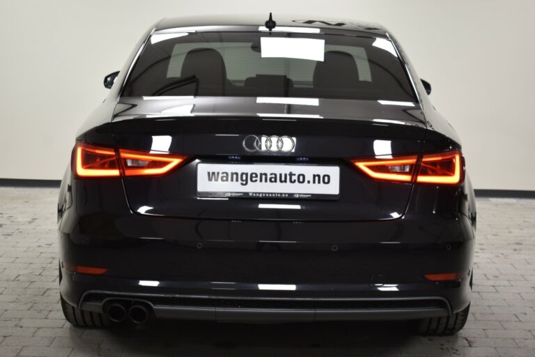 Rear view of a black Audi car with illuminated taillights parked indoors. The license plate reads "wangenauto.no".