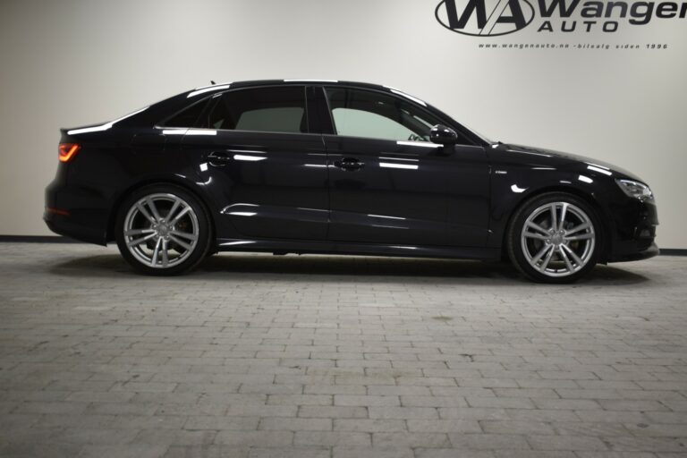 A black sedan parked indoors on a tiled floor with "Wanger Auto" signage on the wall.