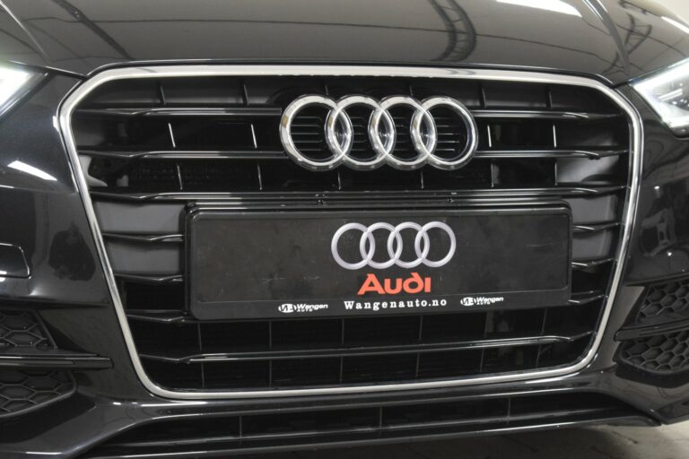 Close-up of a black Audi car grille featuring the Audi logo and a license plate with the text "Audi" and "Wangenauto.no.