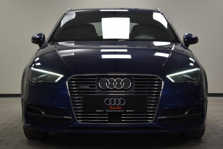 Front view of a blue Audi car with illuminated headlights, displayed indoors on a tiled floor.