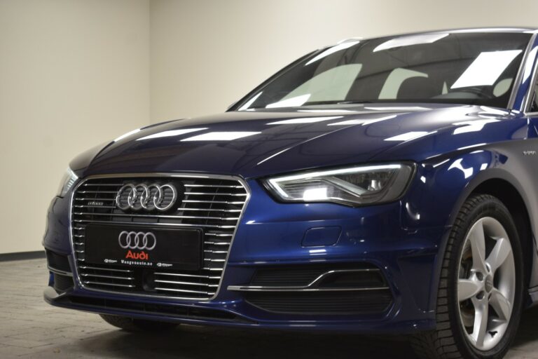 Close-up of a blue Audi car's front, showcasing its grille, headlights, and part of the windshield in a showroom setting.