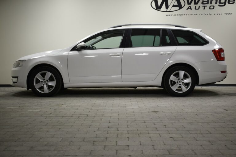 Side view of a white station wagon parked indoors on a gray tiled floor, with a sign on the wall displaying "MAwange Auto.